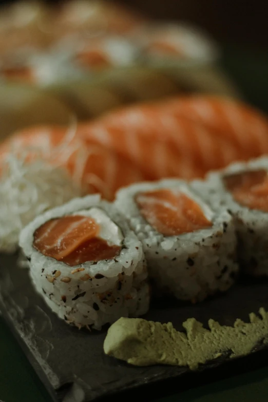 two trays of sushi are on a green counter