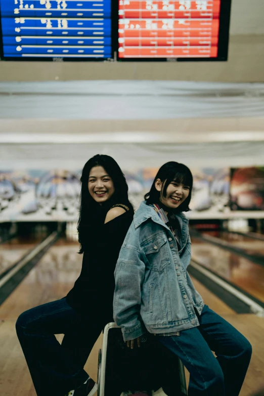 two people sitting next to each other near a bowling lane