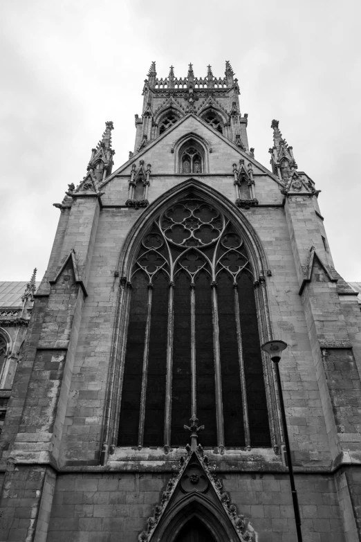 a church's steeple and decorative carvings, against a cloudy sky