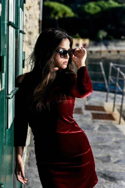 woman in red dress leaning on green metal door