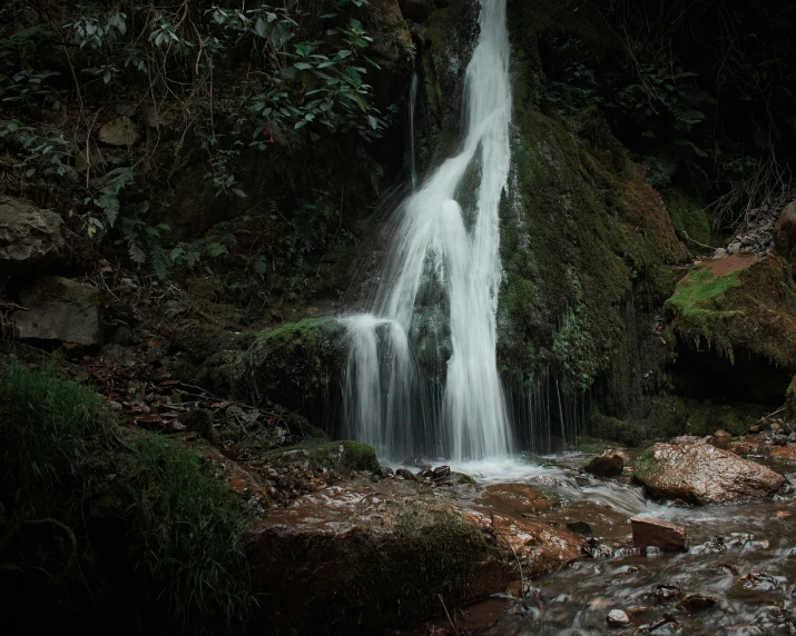 a small waterfall with green vegetation on the side