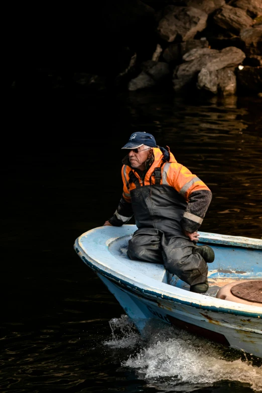 a man is kneeling on the front of a small boat