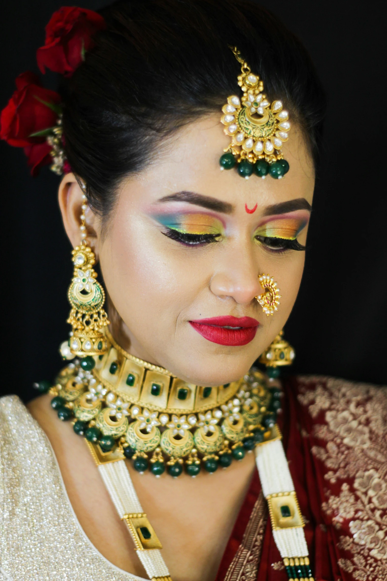 a woman with green eyeshades wearing gold and green jewelry