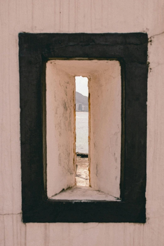 a square window with black frame is on the side of a building