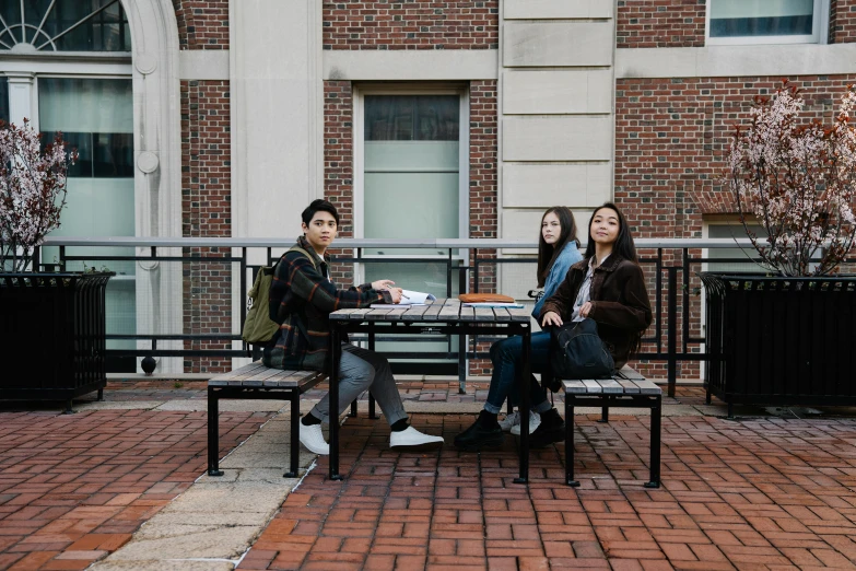 a group of people sitting at a bench by a table