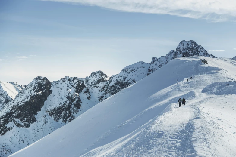 three people are climbing up the mountain on skis