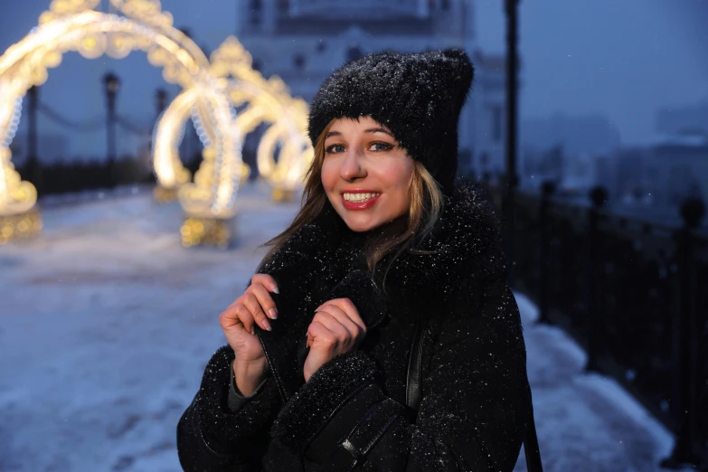 the woman smiles in front of lights and a bridge