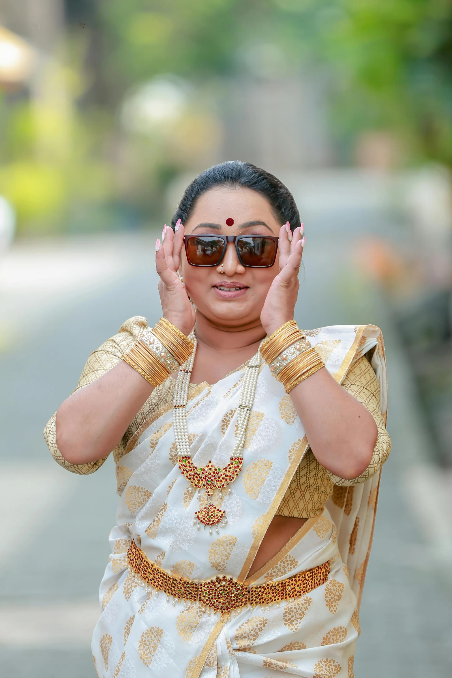 a woman with shades on a street holds her hands up