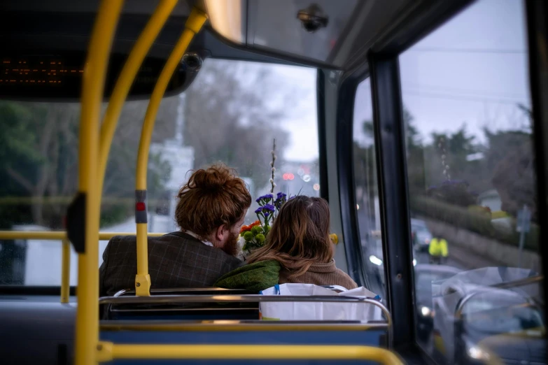 two people sitting on a bus while the bus rides