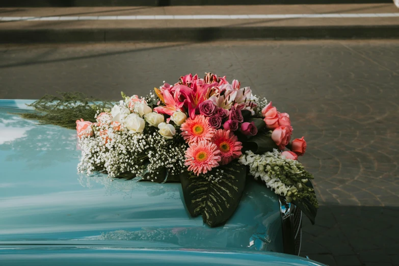 flowers and baby's breath placed on a classic blue car