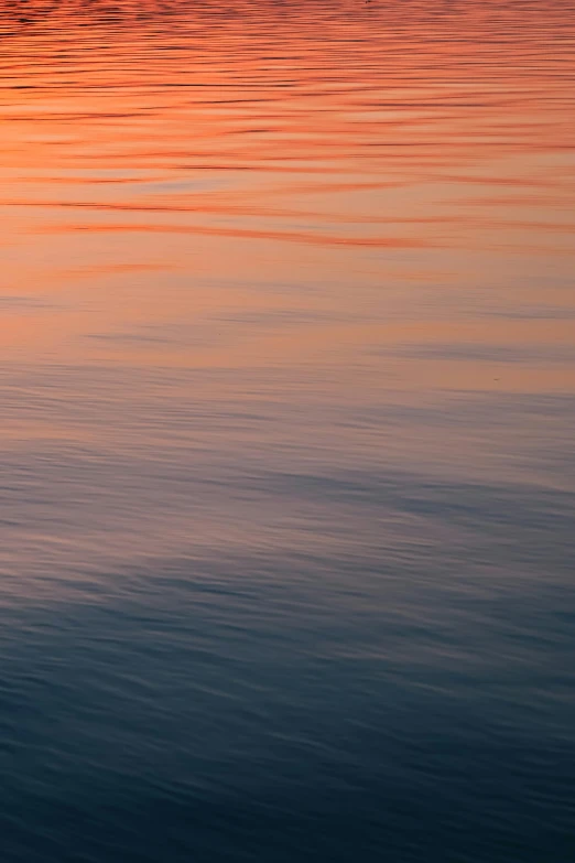 an orange and yellow sky reflects on the water