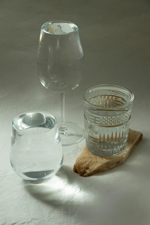 a glass with some water sits next to a glass of water