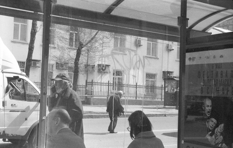 a black and white picture of people walking in front of a bus