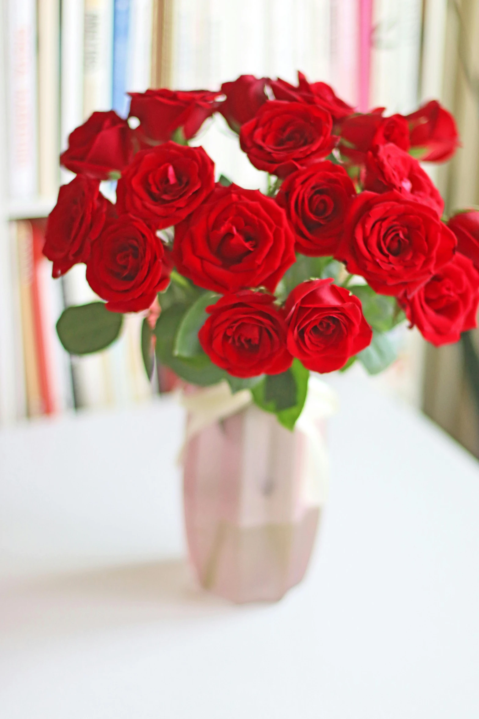 a bouquet of red roses in a pink vase