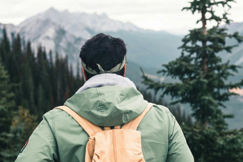 a man wearing a backpack staring out at the mountains