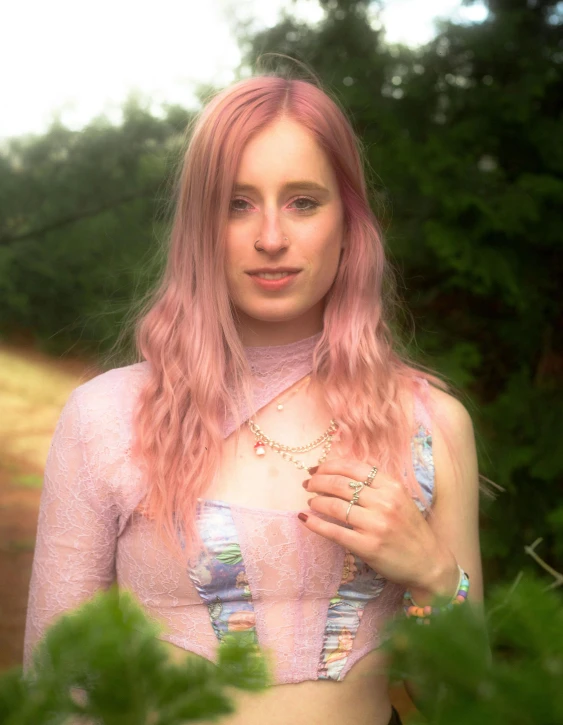 a young lady in a pink top stands outside