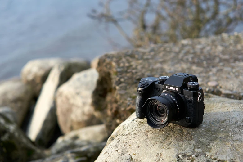 a canon camera is sitting on a rock in front of some water