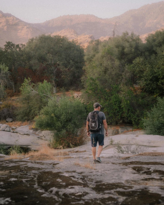 a man walking across a large, rocky riverbed