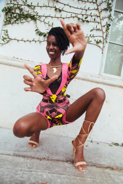 a woman in short shorts and sandals smiles while reaching out for the camera