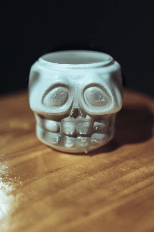 a white ceramic skull on top of a wooden table