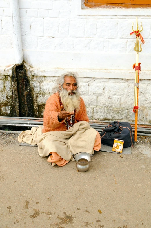 an old man with white beard sitting on the ground