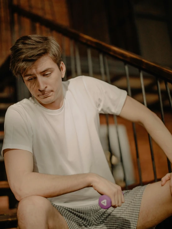 a man holding a tennis racket while sitting on a stair case