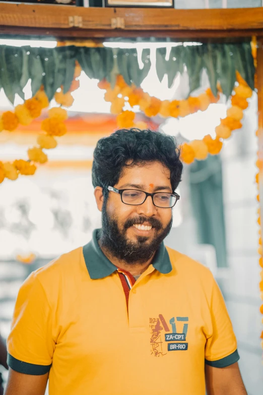 a man wearing glasses in front of orange flowers