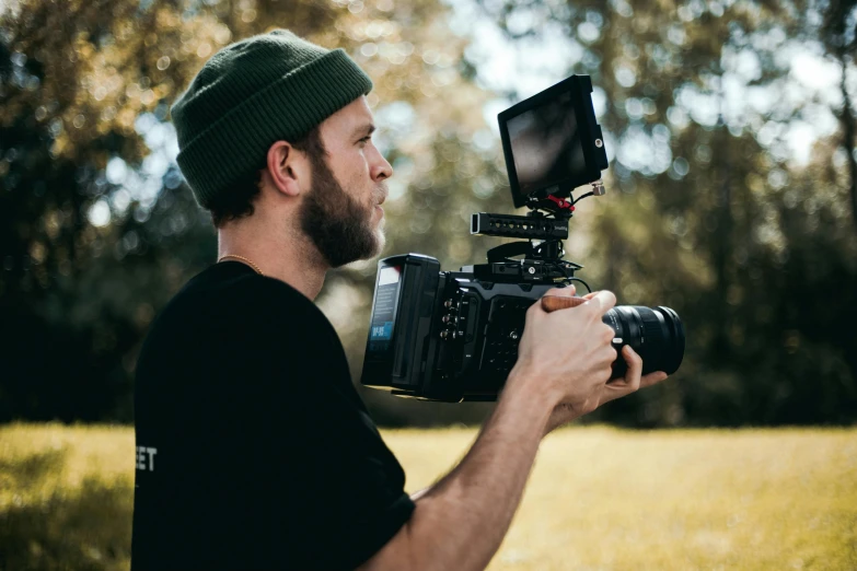 a man holding a camera with trees in the background