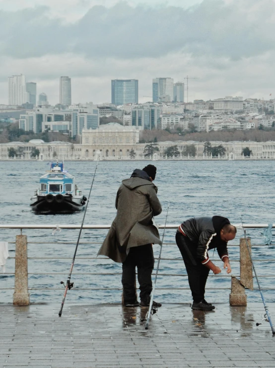 two people fishing off the side of a pier