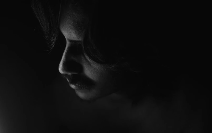 a man with long hair and beard staring in a dark room