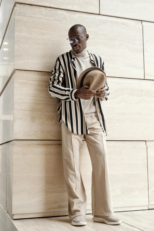 a man wearing a white shirt and blazer leaning against a building