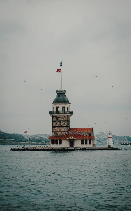 a building with red roof sitting in the middle of a body of water