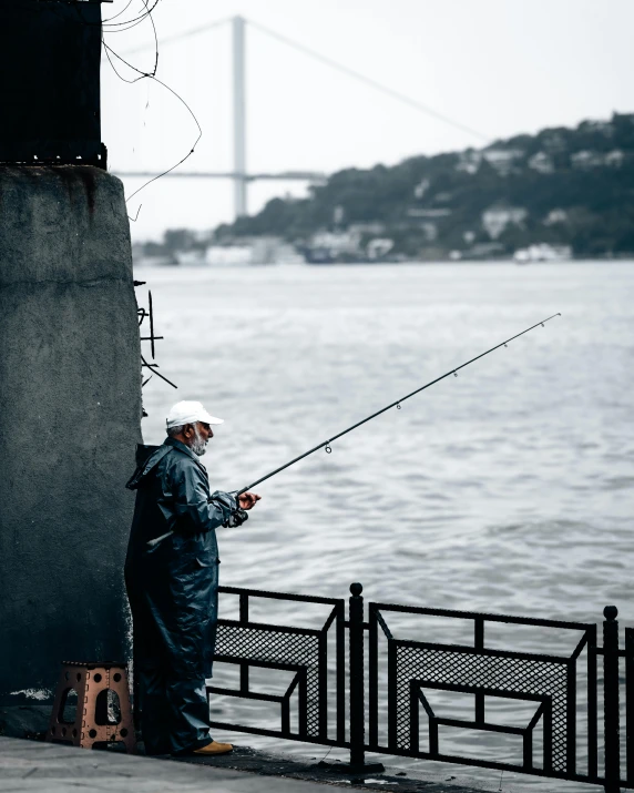 a man standing next to the water with a fishing pole