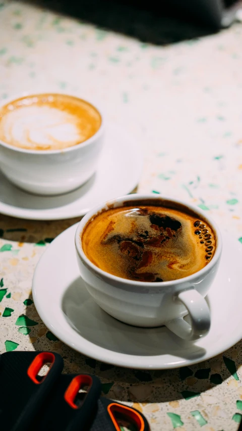 two mugs of cappuccino sit on a table