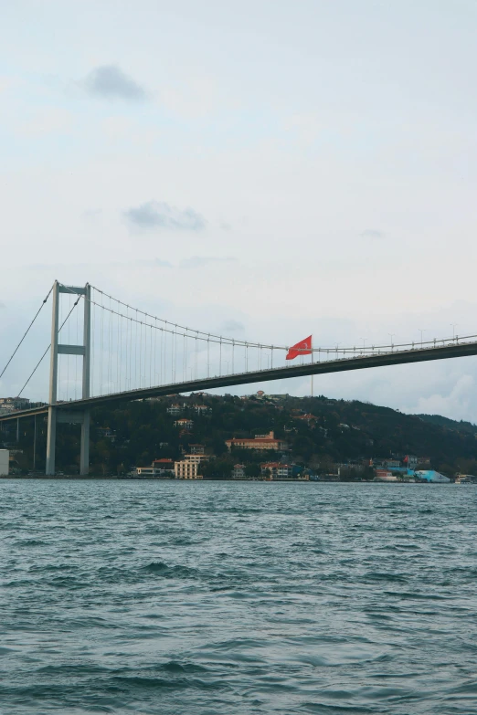 a boat passes under a suspension bridge