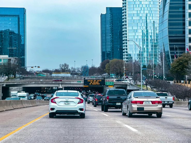 cars and trucks driving through an area with buildings in the background