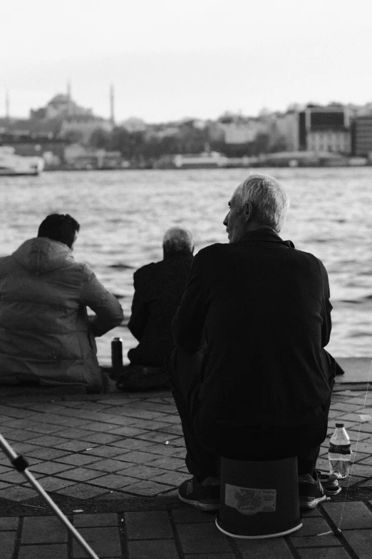 four people sitting on the dock by the water