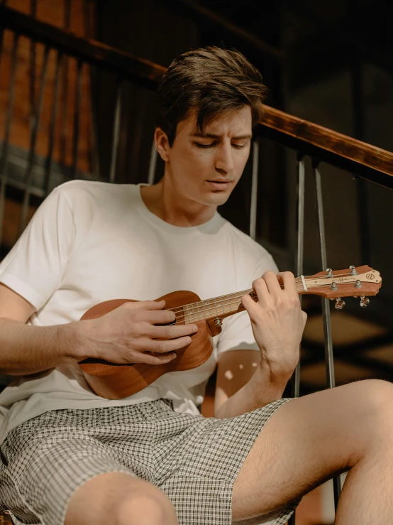 a man in white shirt playing a ukeler