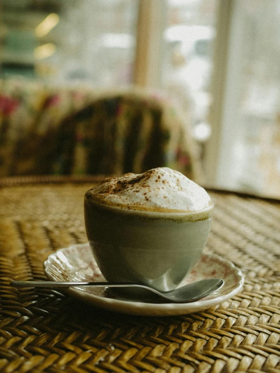 cappuccino on saucer, with spoon on woven tablecloth