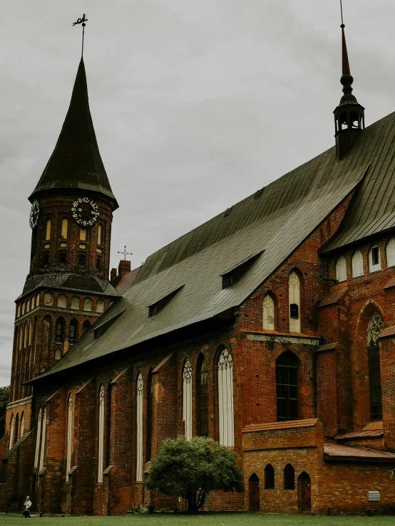 an old red brick church with a clock tower and two large steeples