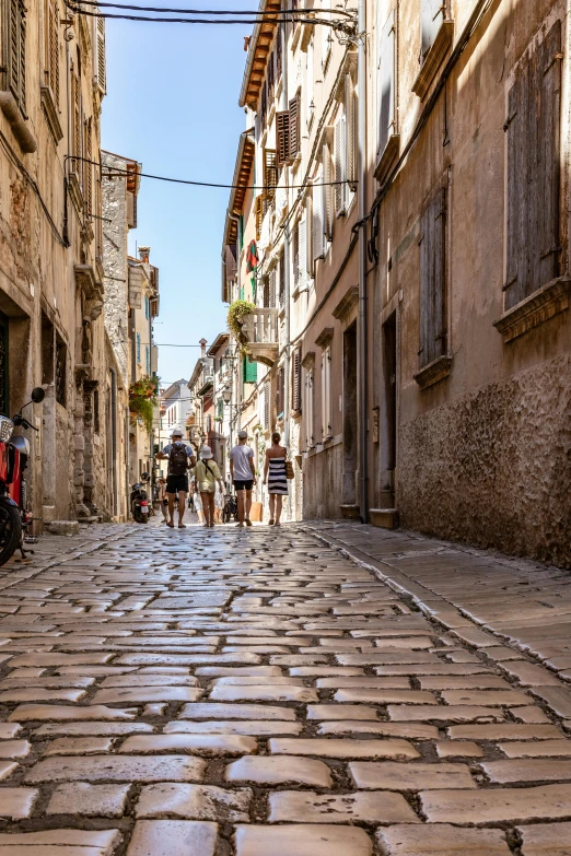 people walk down the narrow cobblestone street