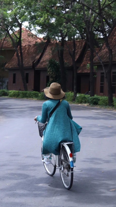 the woman in the hat is riding a bicycle