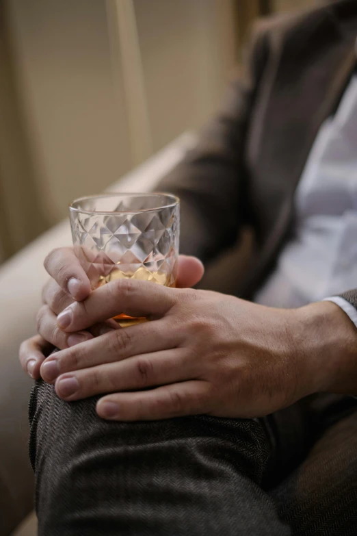 a person holding a glass with gold substance in their hand