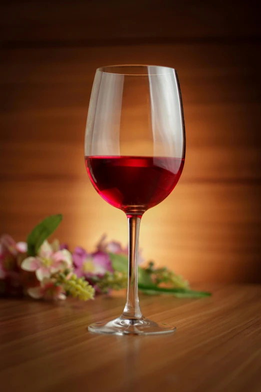 a glass filled with wine sitting on top of a wooden table