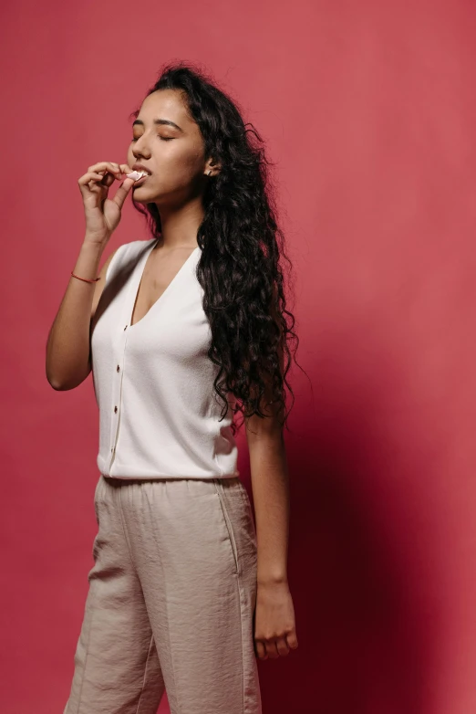 woman posing in front of red wall smoking a cigarette