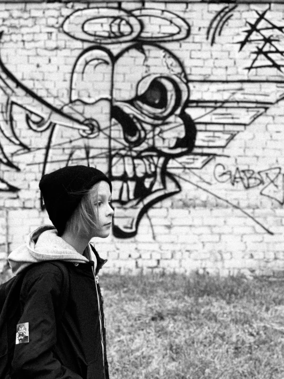 a black and white po shows a boy in front of graffiti