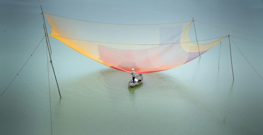 a man riding on a boat in water under a net