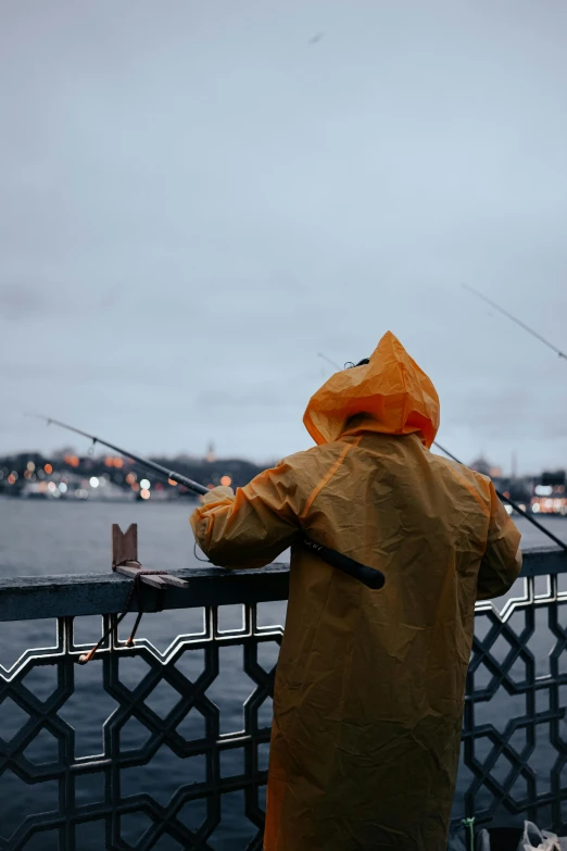 a boy in yellow jacket fishing from pier