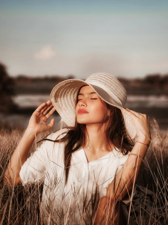 a young woman wearing a hat in the middle of tall grass