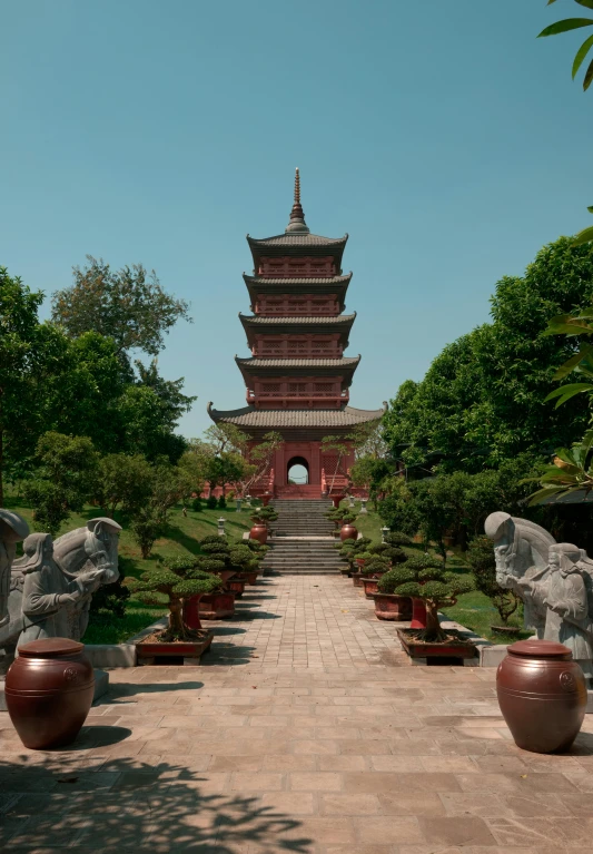 a red building with statues around it is situated in an asian park